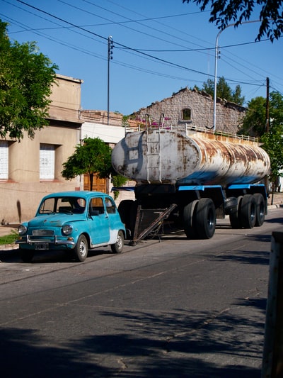 During the day, the blue car beside the white truck
